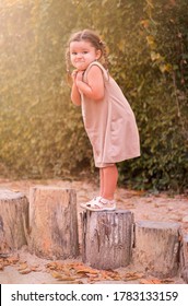 A Frightened Child Stands On A Tree Stump.  Girl Afraid To Take The Next Step. Playground 