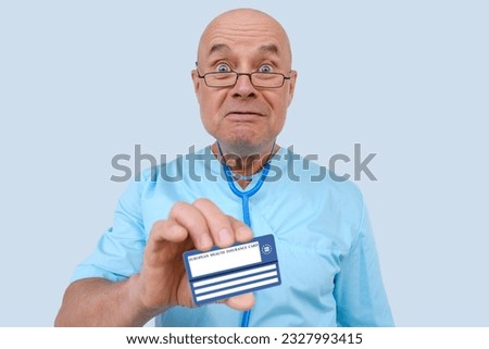 frightened elderly physician with an expressive facial expressions plaintively shows electronic public health insurance cheaper, Insurance Card EU, concept healthcare coverage abroad, healthcare cost