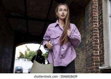 Frightened female is running alone at day time on street. Action. Woman afraid of rapist killer following her. Scared caucasian woman running away from thief. Crime, violence concept
