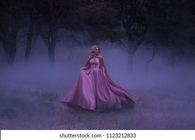A frightened girl blonde runs away from a forest that has covered a thick fog. On the elf, a luxurious pink dress with a long train and a raincoat. Artistic photo.