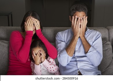 Frightened Hispanic Family Sitting On Sofa And Watching TV