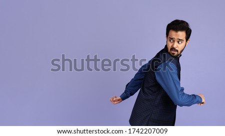 Frightened Indian man running away from something on lilac background, copy space. Panorama
