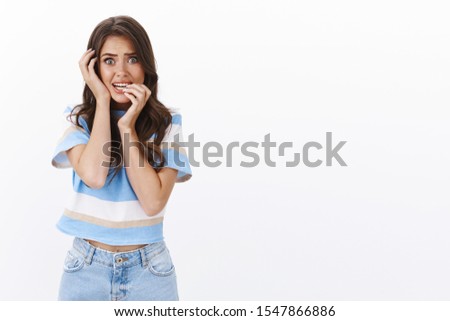 Frightened insecure timid european woman, popping eyes trembling from fear, scared someone inside house, panic look like victim, bite fingernails anxious and terrified, stand white background