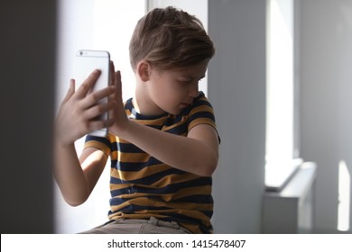 Frightened Little Child With Smartphone Indoors. Danger Of Internet