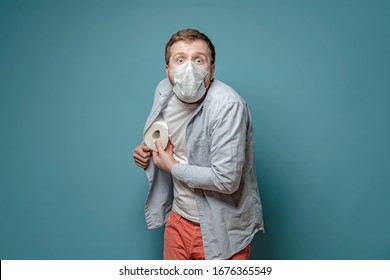 Frightened man in a medical mask in a panic hides toilet paper under shirt, he fears quarantine during a virus outbreak. Paranoia.