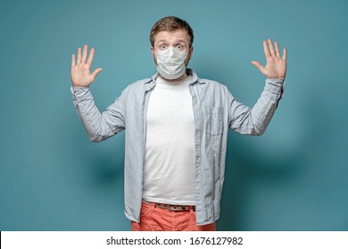 Frightened man in a medical mask wants to avoid the spread of the virus when touched and raises clean hands. Health concept.