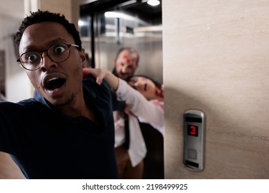 Frightened Man Running From Evil Zombies, Trying To Escape Elevator From Terrifying Scary Walkers. Brain Eating Monsters Chasing And Grabbing Person, Undead Creepy Walking Dead Corpses.