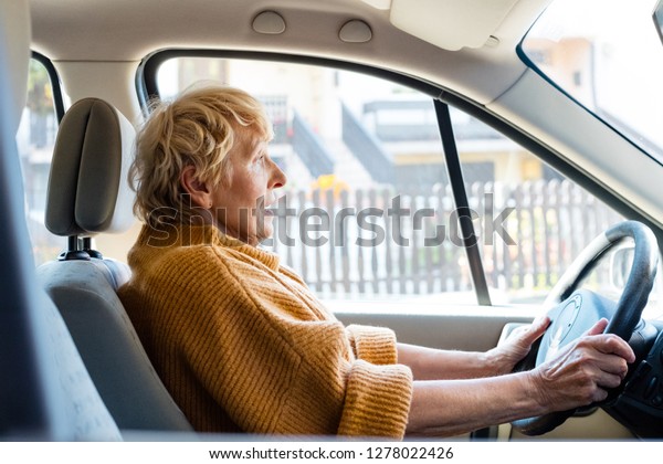 Frightened\
senior woman driving car, having an accident.\

