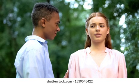 Frightened Teenage Girl Looking Suspiciously At Guy Trying To Hug Her, Ignoring