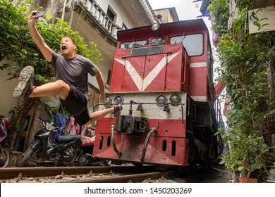 A frightened tourist makes dangerously selfie photo in front of moving train. An undisciplined traveler in the popular Hanoi railway street, Vietnam.