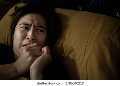 Frightened woman is looking around while lying on her bed,feeling anxious,afraid of shaking,hearing something haunting,symptoms of phobia,hallucinations,sleep deprivation or insufficient sleep chronic