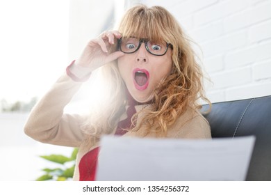 Frightened Woman Looking At The Document Or Bill With Surprise