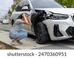Frightened woman sits in front of crashed car