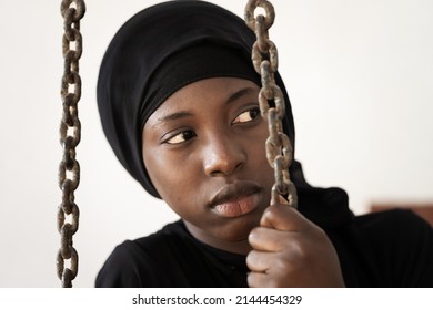 Frightened Young African Girl Behind Chains Symbolizing Imprisonment And The Practice Of Forced Or Arranged Marriage