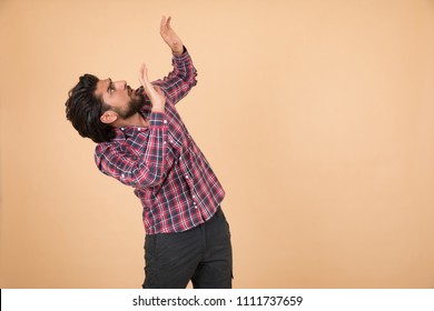 Frightened Young Man Bending Back Looking Up Raised His Arms On The Front Of Him Defend Himself On Orange Background.