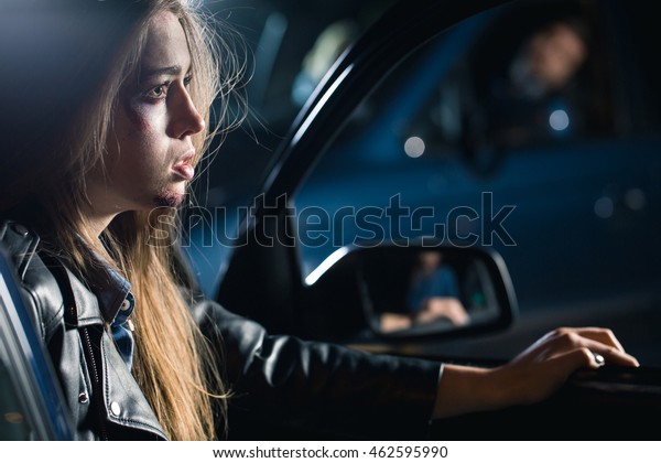 Frightened
young woman with hurt face sitting in the
car