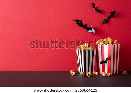 Frightening movie premiere with friends: Side view of a table featuring thematic decor like bats. Couple of popcorn boxes await on a red wall backdrop with blank space for advertising