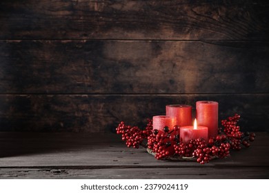 Frist Advent with red berry decoration and candles in a wreath, one is lighted, holiday home decor against a dark rustic wooden background, copy space, selected focus, narrow depth of field - Powered by Shutterstock