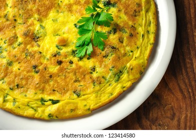 Frittata - italian omelette with parsley and parmesan cheese on a old wooden table
