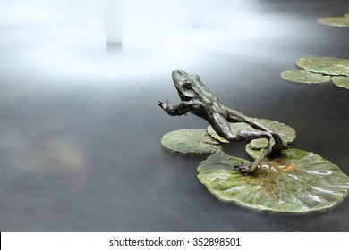 A Frog Jumps Into Water. A Metal Jumping Frog Sculpture. Long Exposure.