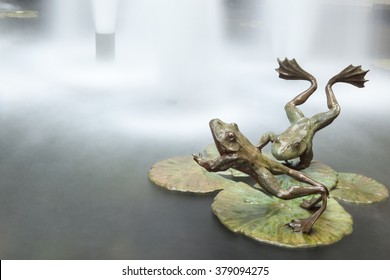 Frogs Jump Into Water. Metal Jumping Frogs Sculpture. Long Exposure.