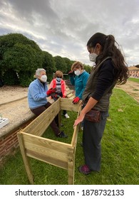 Fromista, Palencia, Spain - October 1, 2020: Women Building Furniture For The Garden Durning The COVID-19 Coronavirus Pandemic, Wearing Protective Face Masks