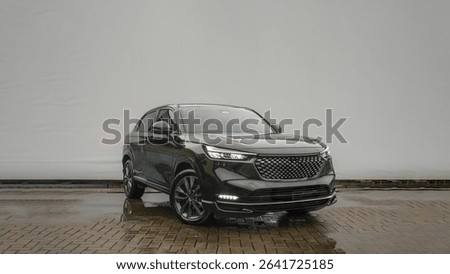 Front angle view of a modern black SUV with LED lights and sporty design parked on a wet pavement with minimalist background and reflections.