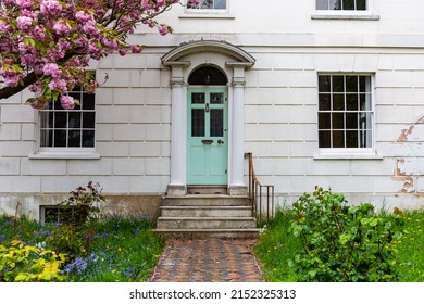 Front Of An Attractive  Traditional Georgian Home In The South Of England With Mint Green Front Door Flanked By Neo Classical Columns And A Checkboard Path Leading Up To Steps