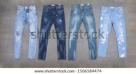 Front and back view four blue,  torn jeans close-up–gray background