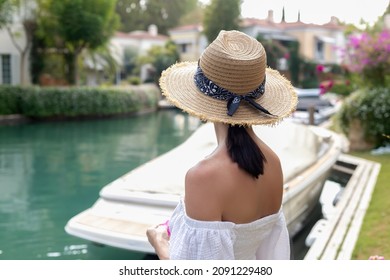 Front Behind Of A Woman Walking Along The River Of A Luxury House With Beautiful Landscaping On A Bright, Sunny Day, Modern Design.