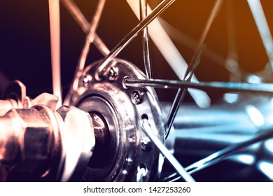 Front Bicycle wheel with spokes. The wheel sleeve is shiny metal. Spokes are chrome. The background is blurred.
