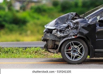 Передняя часть черного автомобиля повреждена в результате аварии на дороге