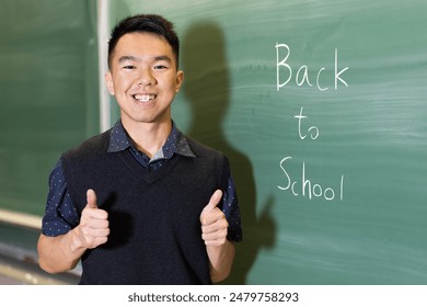 In front of a blackboard that reads back to school, a teenage boy is smiling and giving a thumbs up gesture. - Powered by Shutterstock