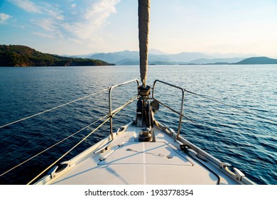 The front bow of a white sailing boat with blue sky and sea background. Islands and clouds at horizon. Love in blue with copy space