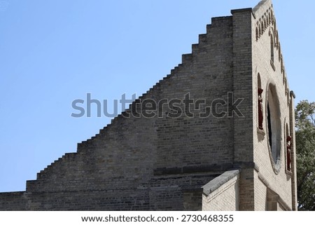 front, brick side wall of preserved historic faith building in sun, shadow under clear blue summer sky (landscape, ruins)