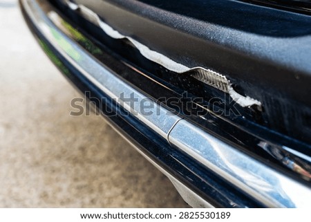 Front bumper show torn, detached, peeling and broken lower rubber skirt lip or trim beneath under grille. Vehicle wear and tear,  Damaged front bumper and torn rubber lip of car. Loss of adhesion.