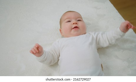 In Front Of The Camera Charismatic Pretty Baby Laying Down On The Bed And Giving Hands To Standing Up To Her Mother Concept Of Childhood And Maternity