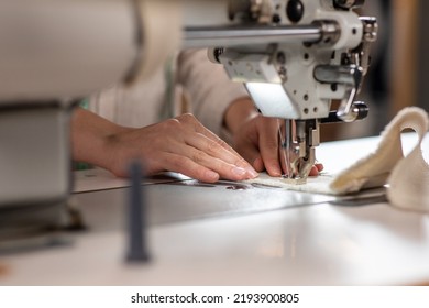 In front of the camera good looking dressmaker using her professional sewing machine to sew a dress closeup taking video details - Powered by Shutterstock