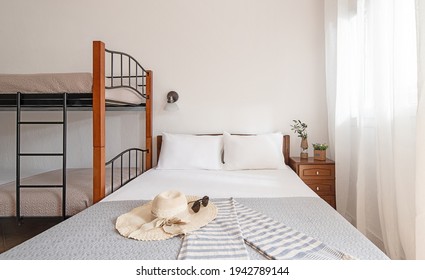 Front Closeup View Of Simple Style Interior Bedroom With Classic Double Bed And Bunk Bed With Metal Stairs, Wooden Furniture, On White Empty Wall Copy Space Background