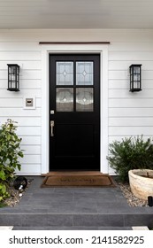 Front Door, Black Front Door With A White Wall, Light Fixtures And Potted Plants