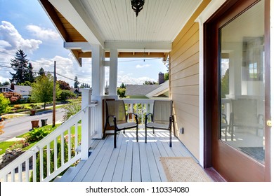 Front Door Entrance With Steps And Two Chairs Under Covered Porch.