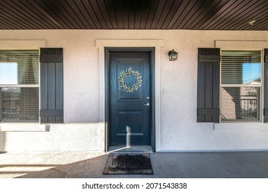 Front door exterior with dark wood plank ceiling and windows