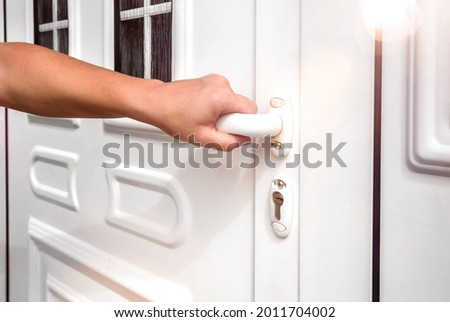 front door. hand holds doorknob on front door PVC 
