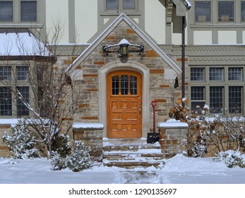 Front Door Of House On A Sunny Winter Day With Bushes Covered By Snow