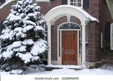 Front Door Of House With Snow Covered Pine Tree