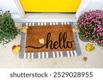 Front door mat with autumn leaves and mum flowers. Yellow front door. Mat says 