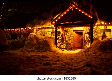 Front Door Of Night Lit Stone Lodge In Winter Snow At Christmas