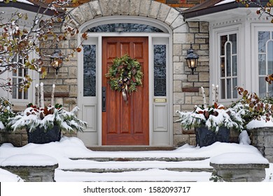 Front Door Of Snow Covered House With Christmas Wreath