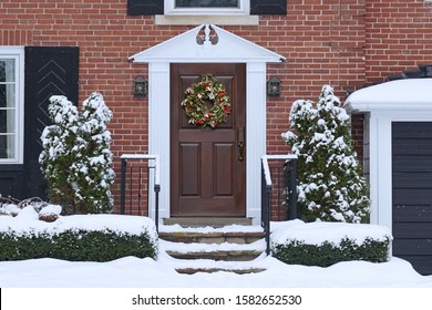 Front Door Of Snow Covered House With Christmas Wreath