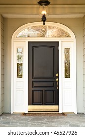 Front Door Of An Upscale Home With An Illuminated Porch Light. Vertical Format.